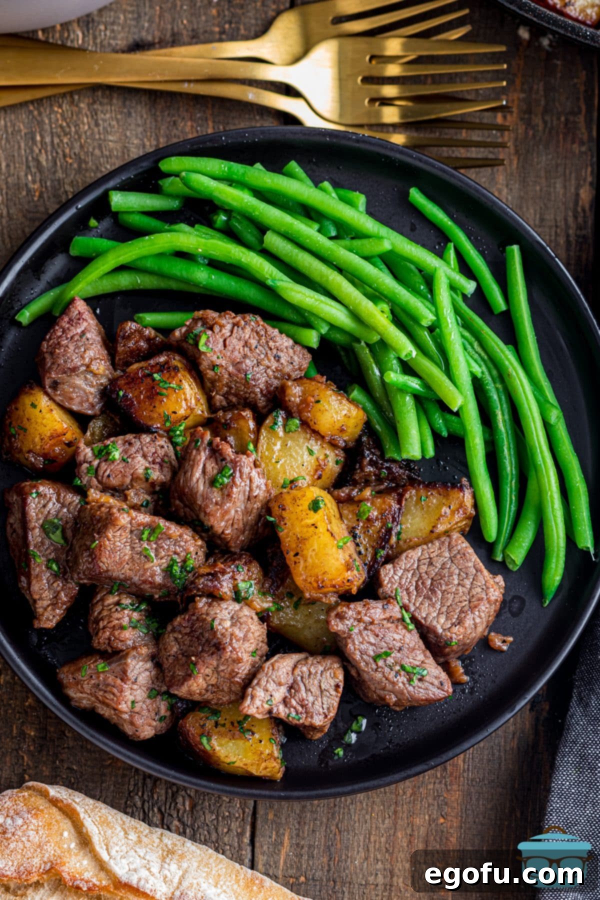 Pan-Seared Garlic Butter Steak Bites with Crispy Potatoes 2 A plate of Garlic Butter Steak Bites and Potatoes with a side of fresh green beans.