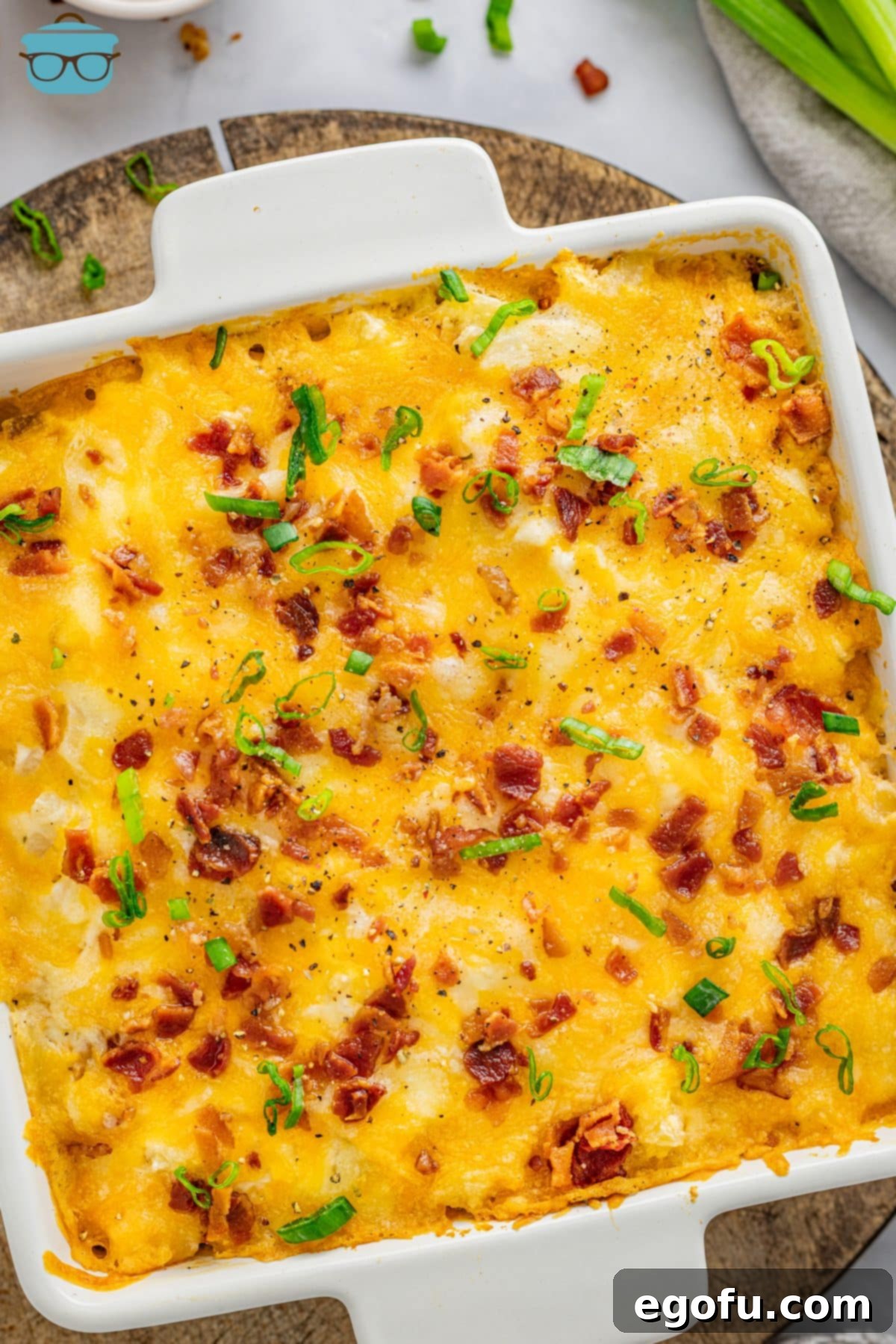 Looking down on a full casserole dish of Cheesy Chicken Hash Brown Casserole, garnished with green onions.