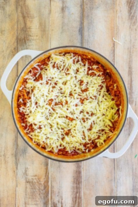 Cheese being added to a casserole skillet.