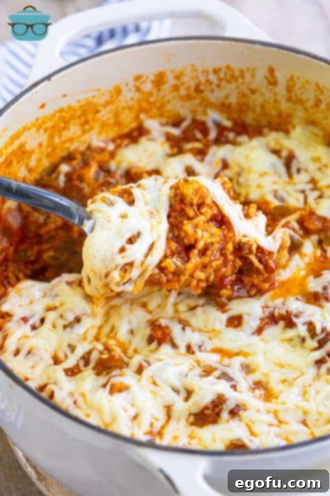 A cheesy scoop of Italian Rice Casserole being lifted from the pot.