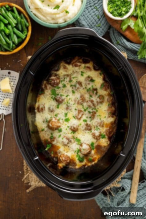 Fully cooked French Onion Meatballs in a crock pot, topped with melted mozzarella cheese.