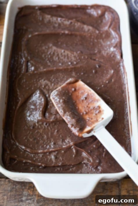 Pudding being spread with a rubber spatula in a baking dish.
