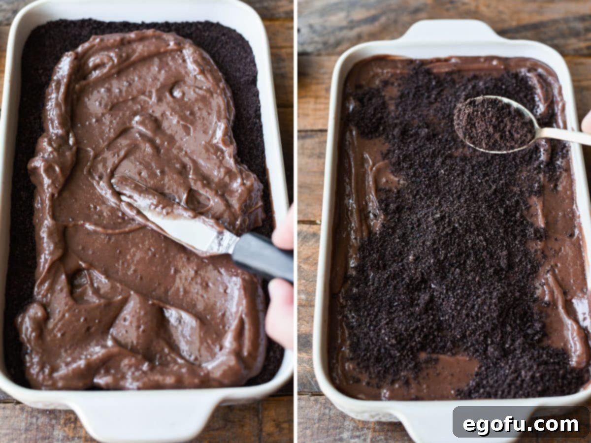 A knife spreading more chocolate pudding over the first layer of pudding and Oreo crumbs, followed by more Oreo crumbs.