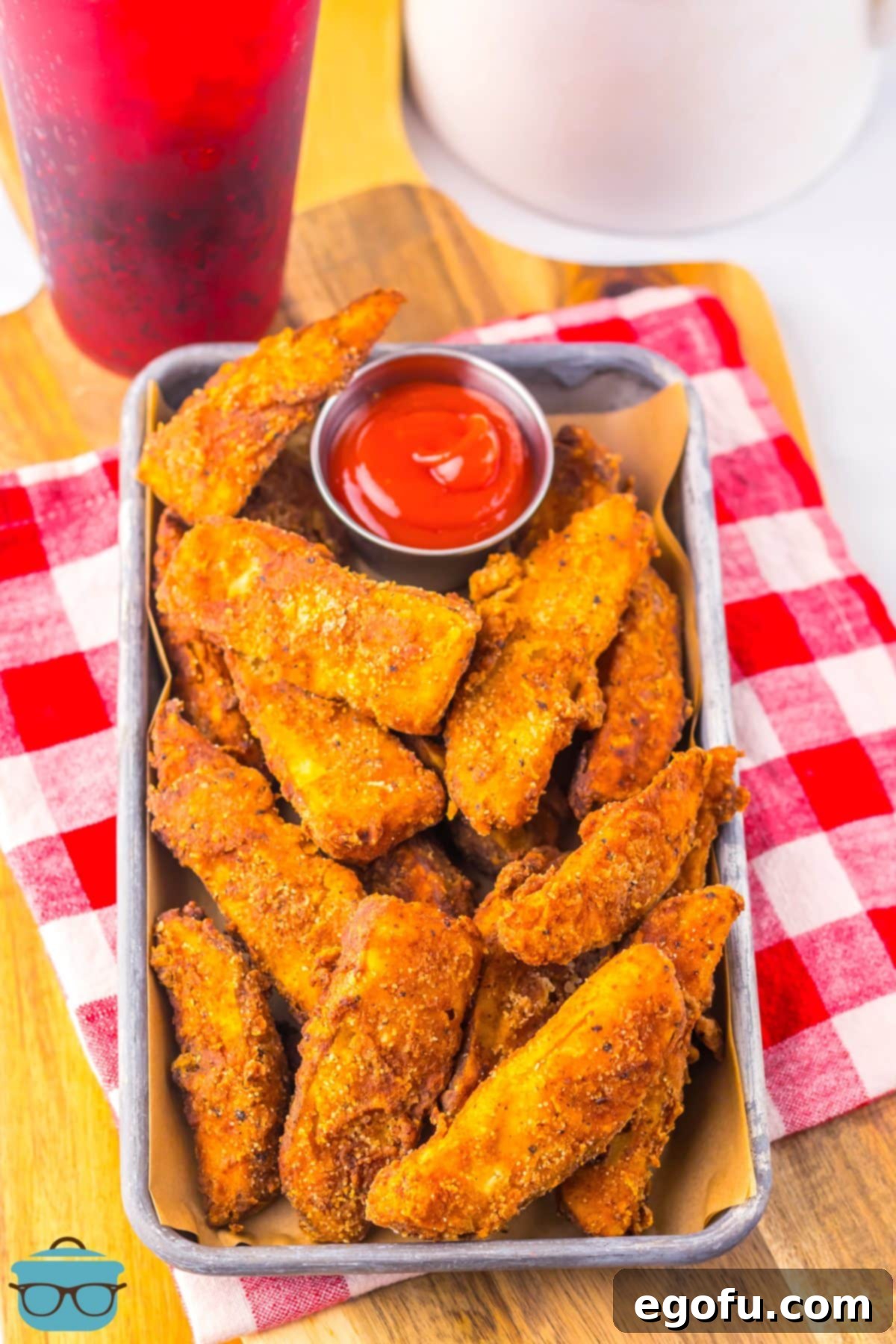 A few KFC Potato Wedges on a metal tray with ketchup for dipping.