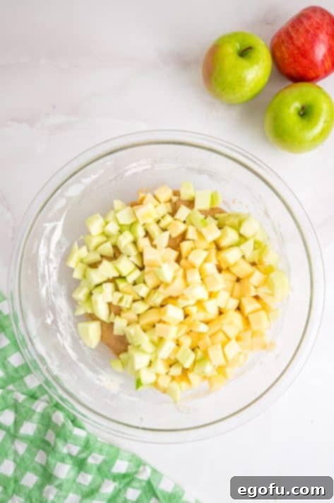 Cake batter being mixed with dry ingredients, followed by the folding in of diced apples.