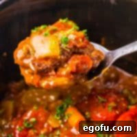 A serving utensil holding a scoop of Crock Pot Swiss Steak above the Slow Cooker.