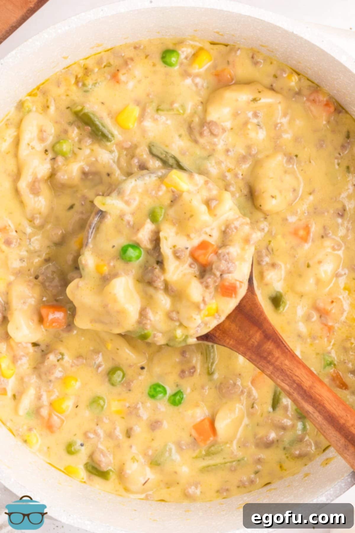 Looking down on a big bowl of Ground Beef and Dumplings with a spoon stirring and getting some.