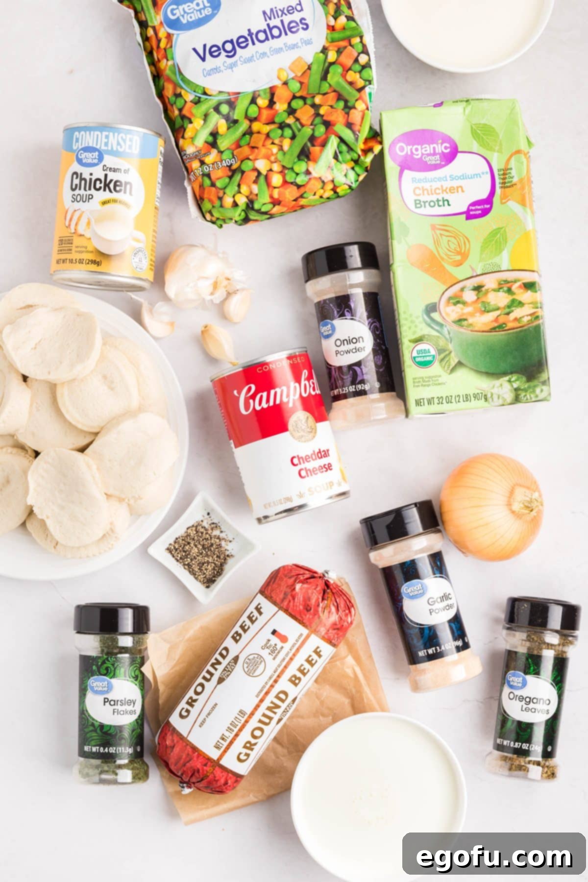 Ground beef, diced yellow onion, minced garlic, low-sodium chicken broth, frozen mixed vegetables, condensed cheddar soup, condensed cream of chicken soup, milk, heavy cream, dried oregano, dried parsley, garlic powder, onion powder, black pepper, and refrigerated biscuit dough.