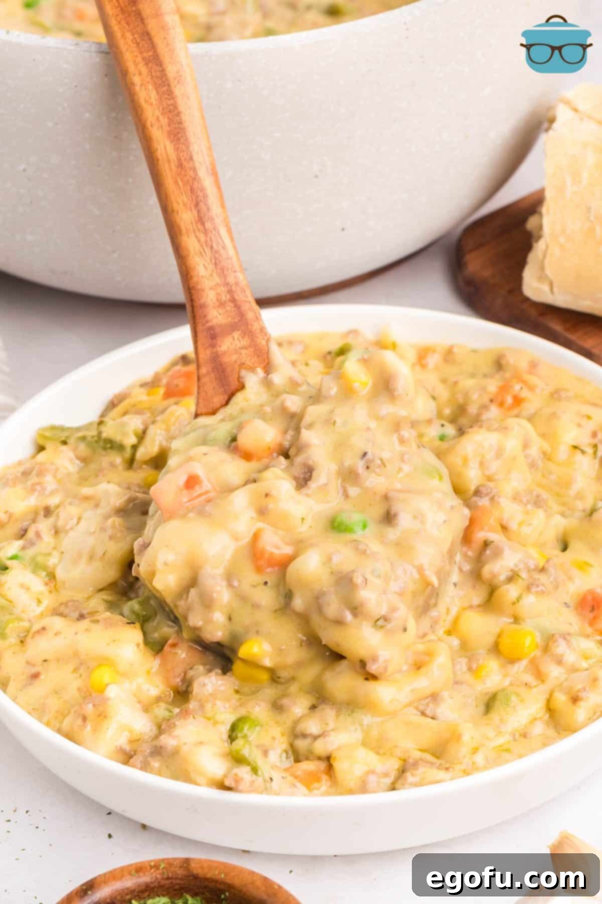 A wooden serving utensil getting a scoop of Ground Beef and Dumplings.