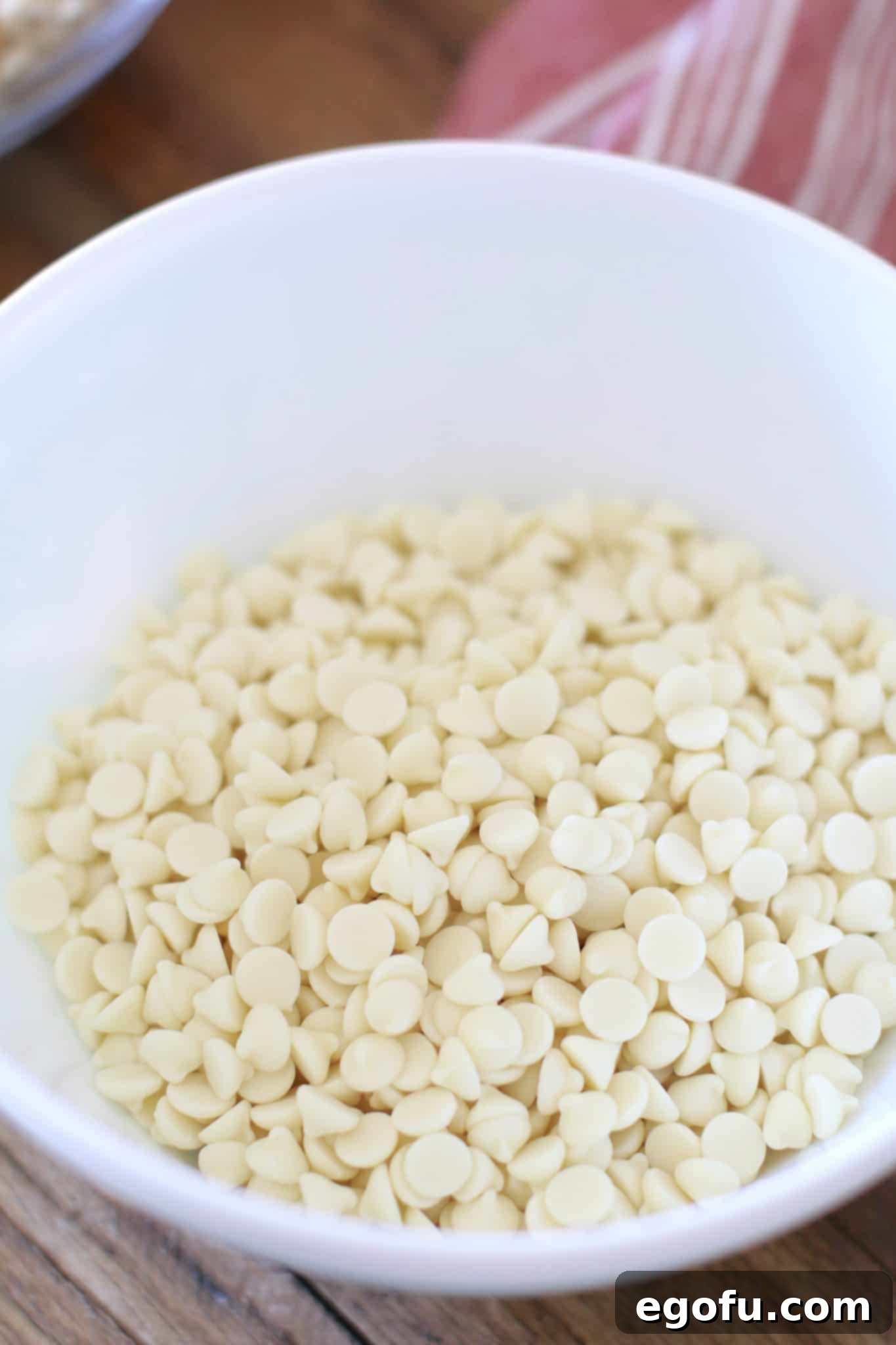 White chocolate chips in a microwave-safe bowl, showing their readiness for melting into a smooth, creamy mixture.