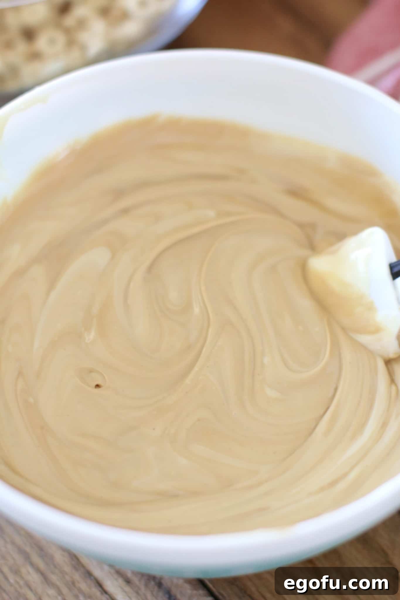 Melted peanut butter, cookie butter, and white chocolate in a bowl, showcasing its smooth and perfectly pourable consistency.