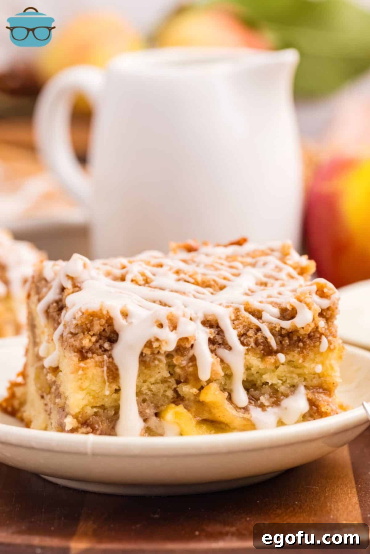 A small slice of homemade Apple Coffee Cake, showcasing the fluffy cake layers, tender cinnamon apples, and generous streusel topping, finished with a sweet glaze.