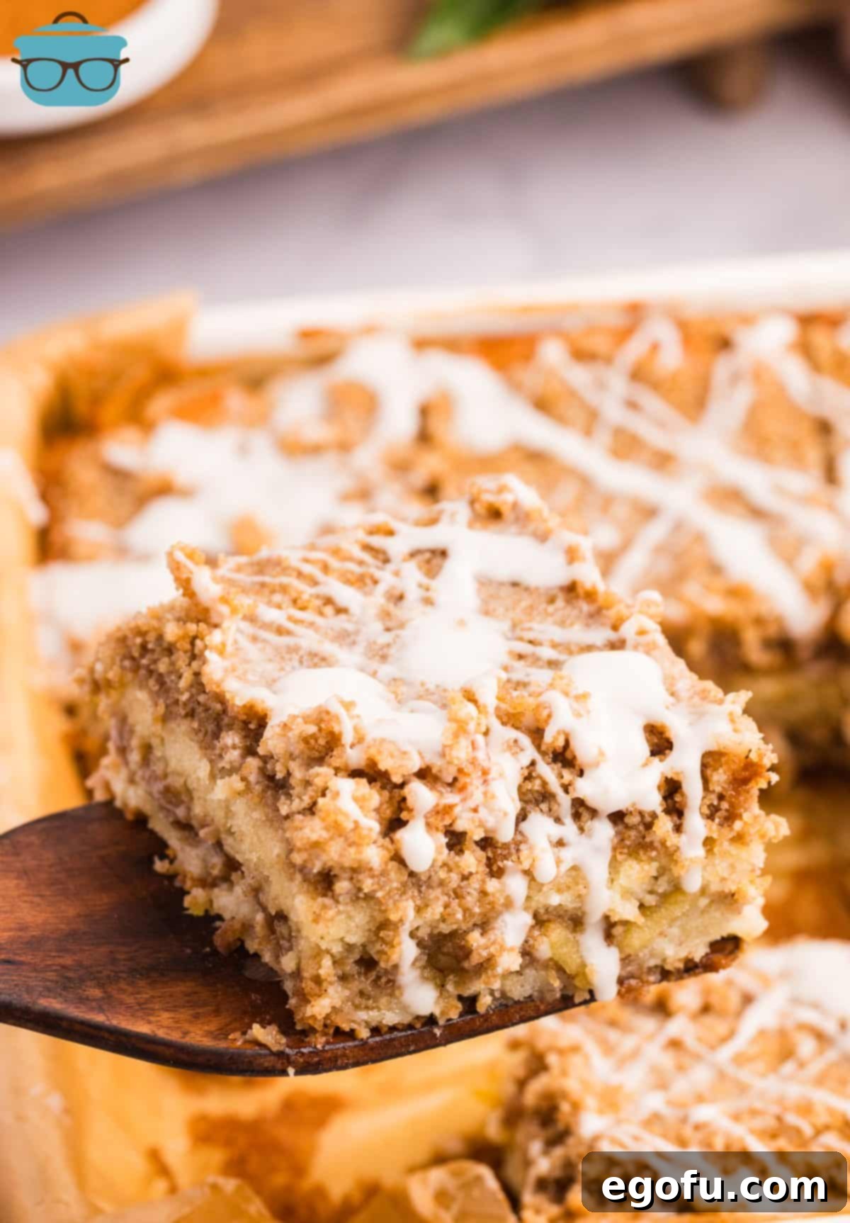 A perfectly baked and cooled slice of Apple Coffee Cake being carefully lifted from the baking pan with a wooden spatula, ready to be plated and enjoyed.