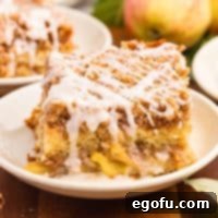 A dessert plate with a slice of Apple Coffee Cake and icing.