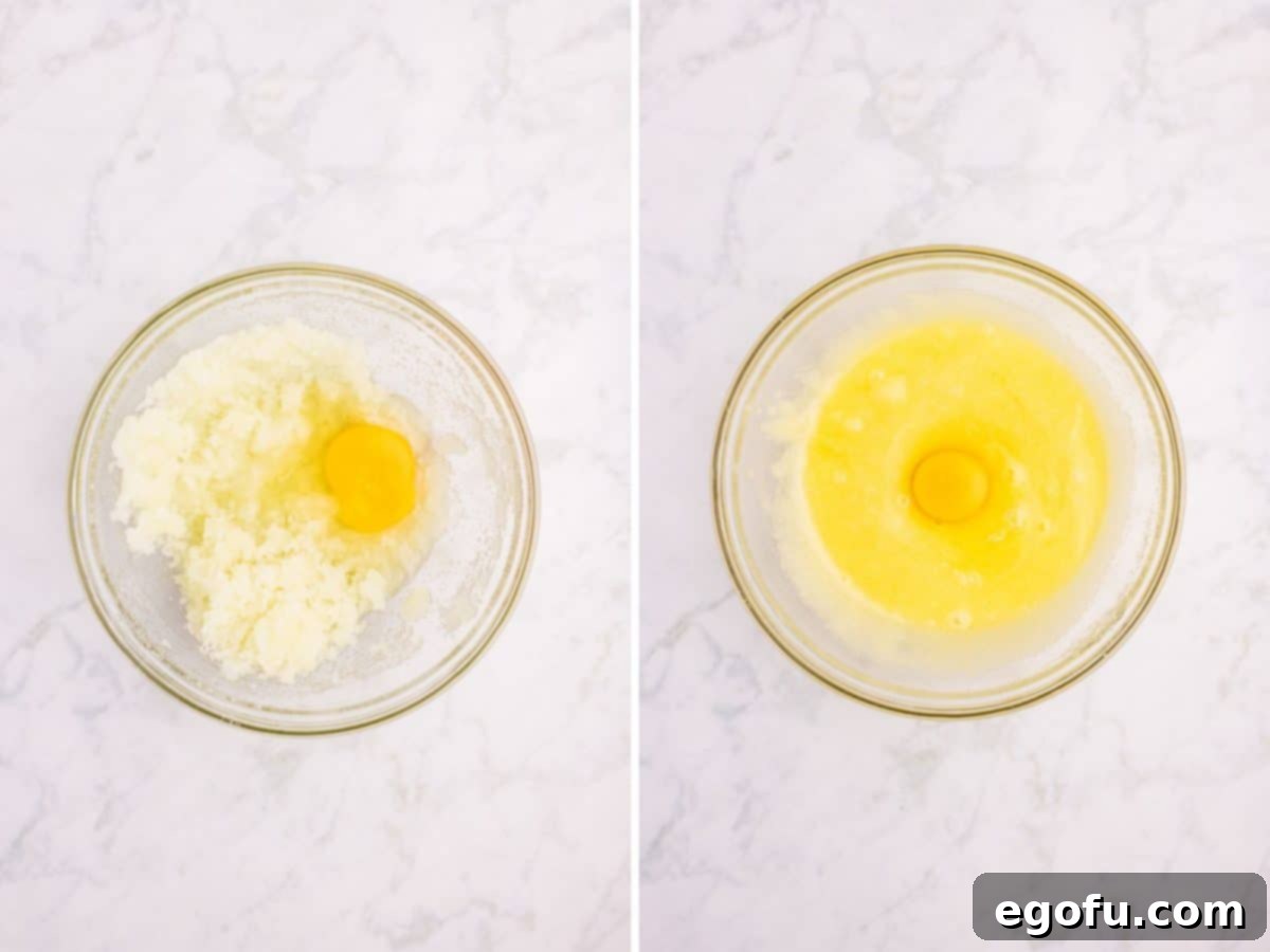 Two eggs being carefully added, one at a time, to the large mixing bowl containing the wet batter ingredients, being beaten in.