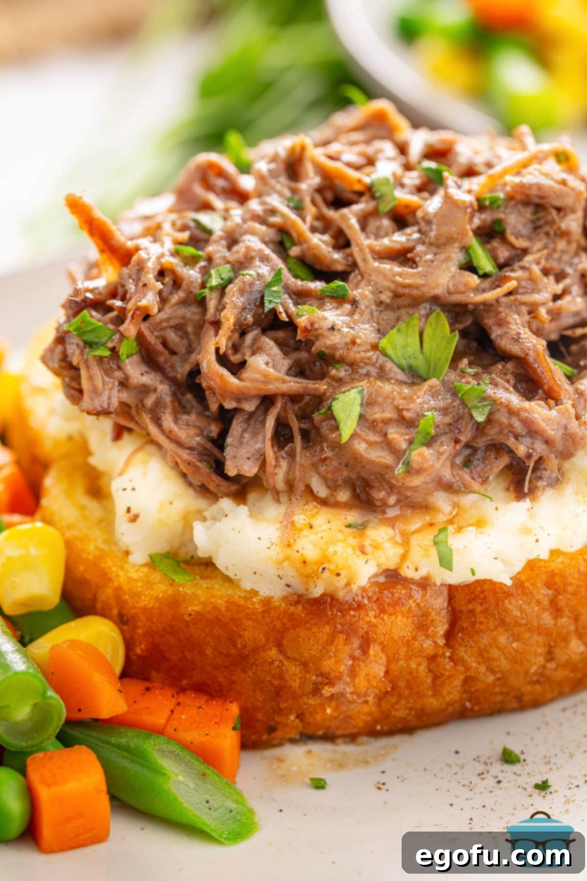 Close up looking at a slice of bread with mashed potatoes and Beef Manhattan.
