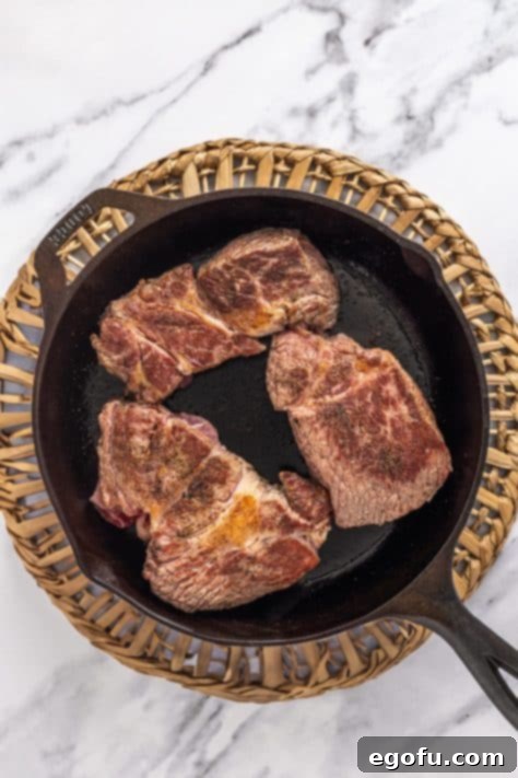 Beef being seared in a skillet.