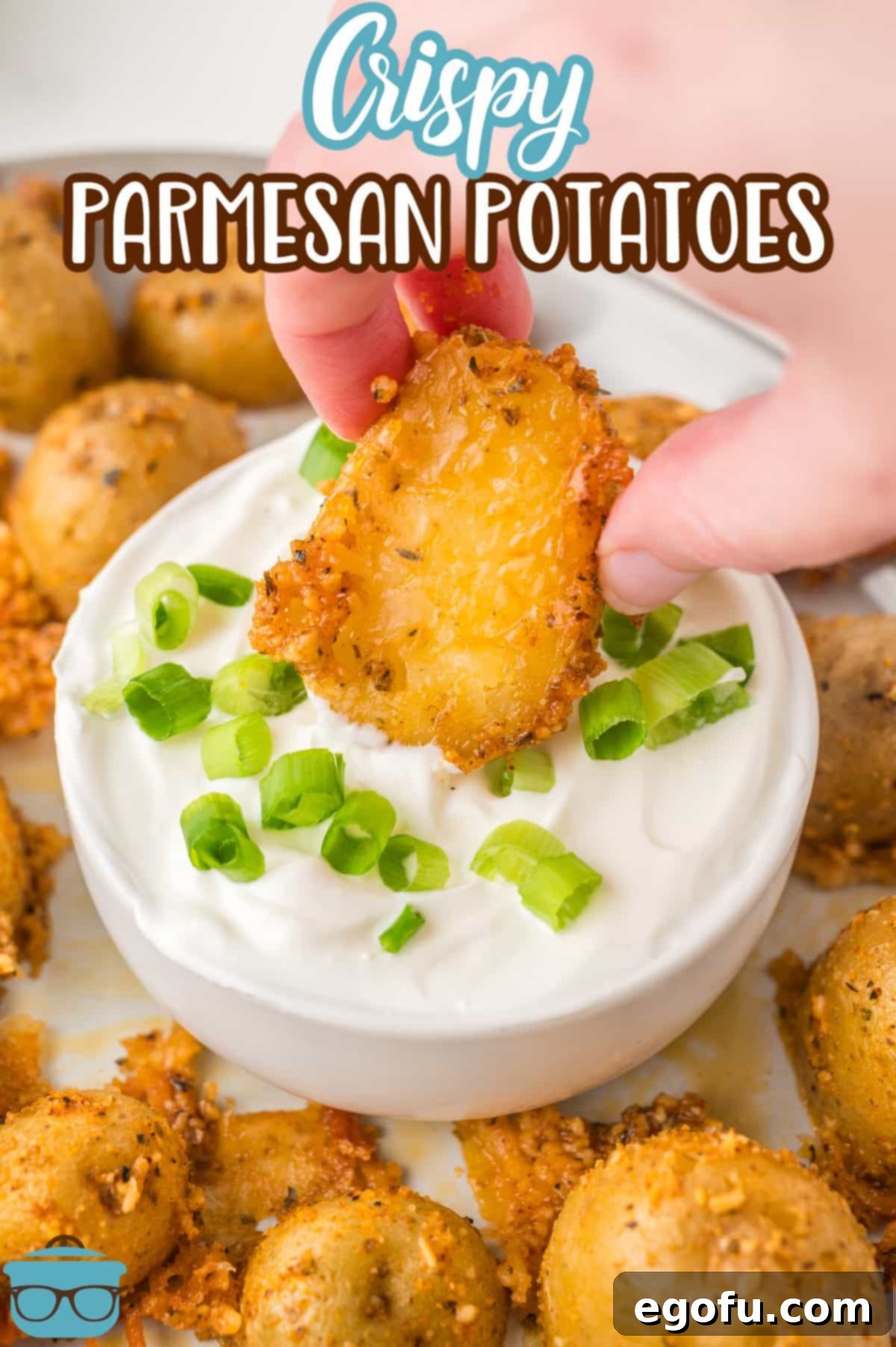 A hand dunking a Crispy Parmesan Potato in the sauce.