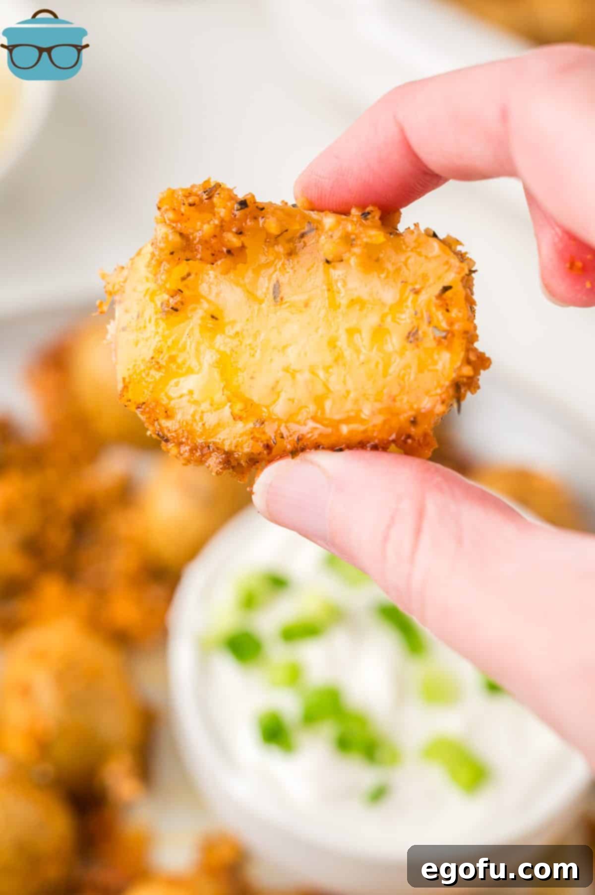 A hand holding a Crispy Parmesan Potato above the rest.