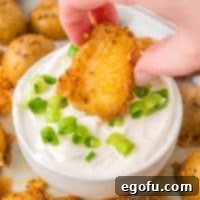 A hand dipping a Crispy Parmesan Potato in the dipping sauce.