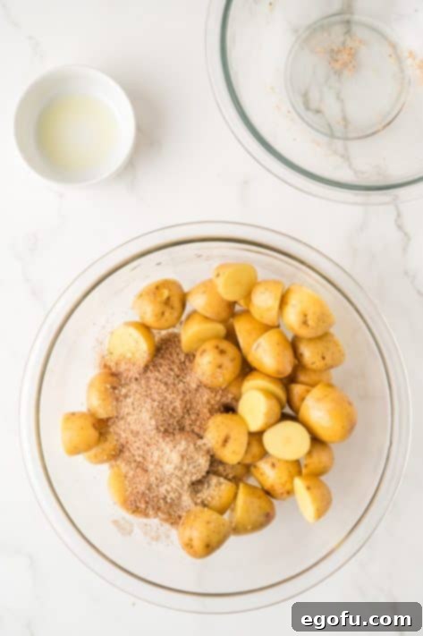 Olive oil and spices with potatoes in a bowl.