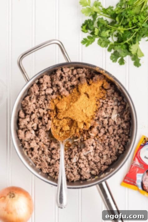 Slow Cooker Fiesta Lasagna 11 Water and taco seasoning being added to ground beef and onions.