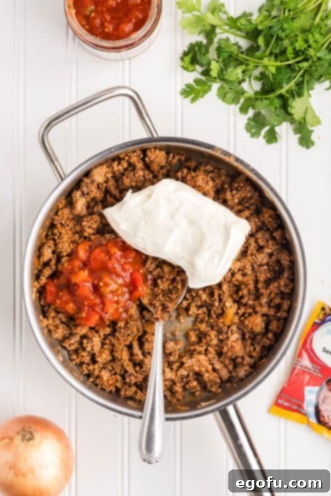 Slow Cooker Fiesta Lasagna 12 Salsa and cream cheese being added to taco meat mixture.