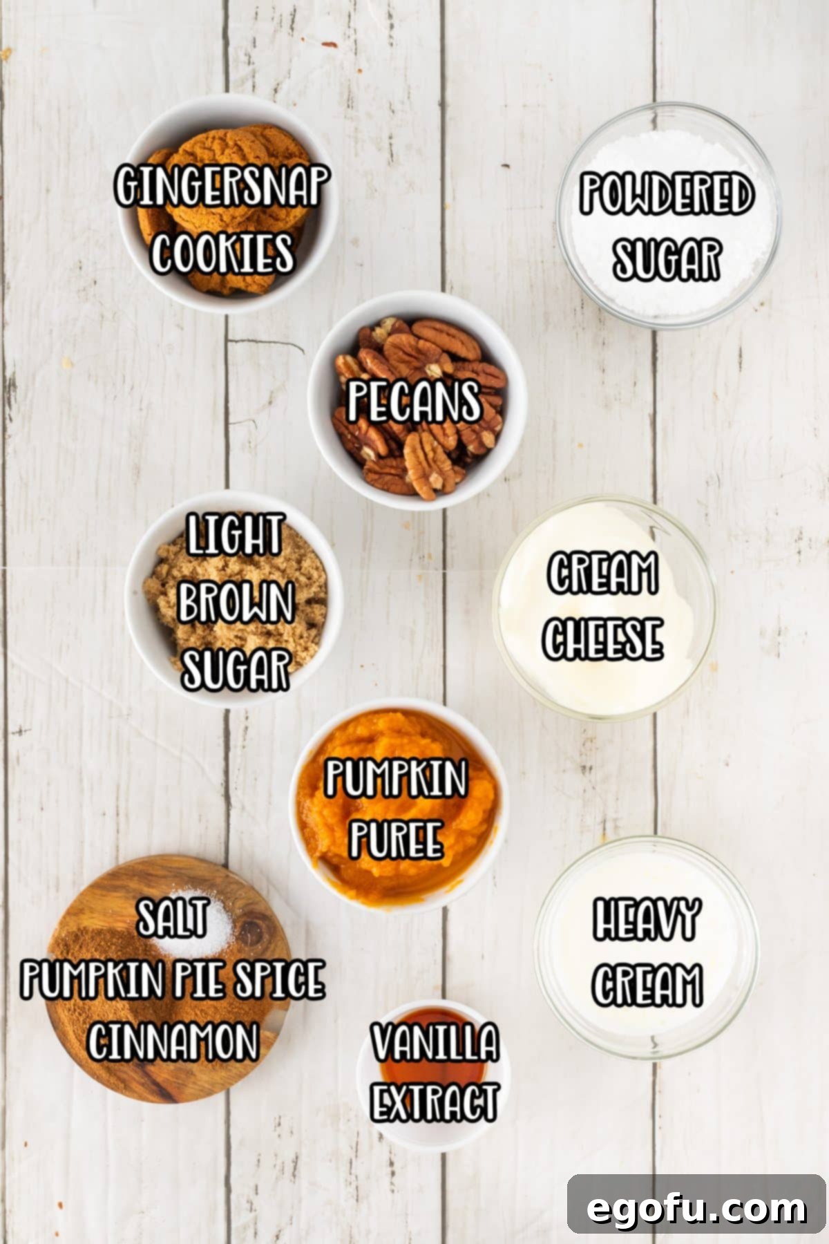 A collection of ingredients laid out: Pumpkin puree, heavy cream, light brown sugar, pecans, cream cheese, pumpkin pie spice, powdered sugar, ground cinnamon, vanilla extract, and ginger snap cookies.