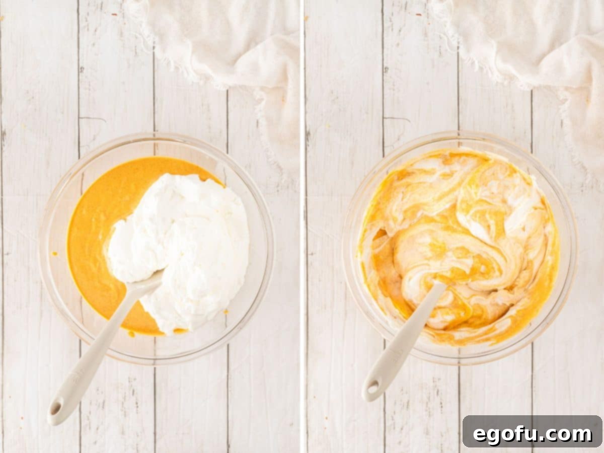 The fluffy whipped topping being gently folded into the rich pumpkin filling in a mixing bowl.