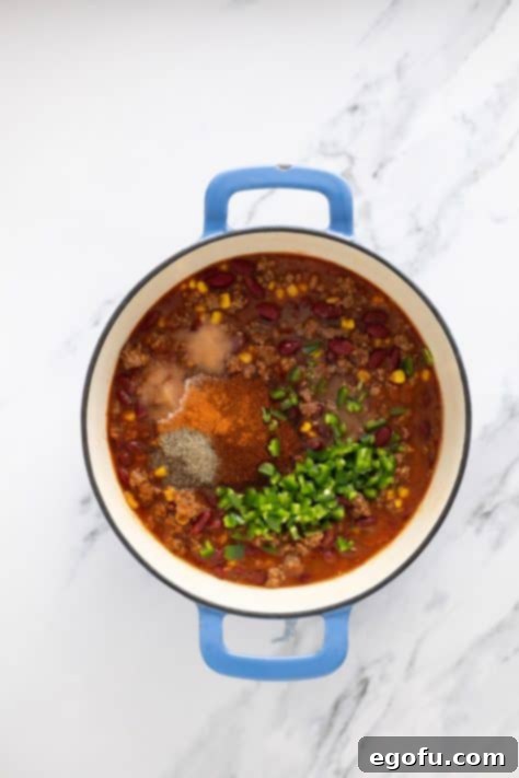 Golden Cornbread Chili Bake 10 A Dutch oven with ingredients for chili with cayenne pepper, chili powder, salt, pepper, sugar and jalapeno just being added.