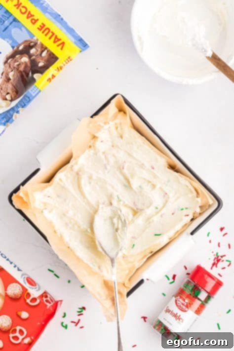 Creamy Cloud Bites 14 Cool Whip mixture being transferred to a lined baking dish, smoothing it out for even chilling.