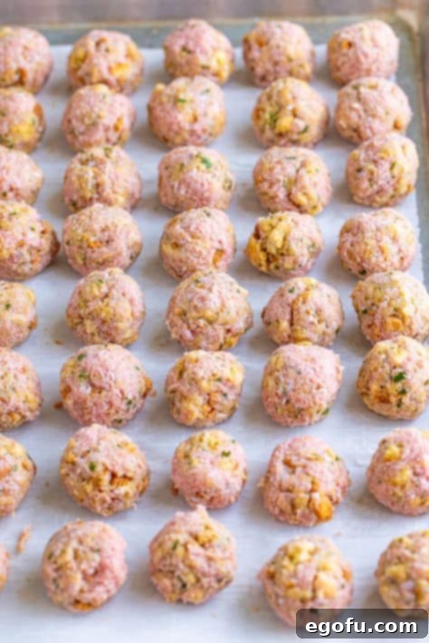 Unbaked turkey meatballs on a lined sheet pan.