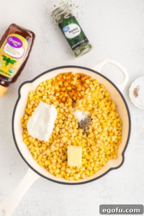 A skillet with frozen corn, cream cheese, butter, salt, pepper, parsley, and honey.