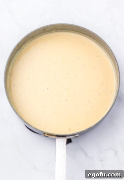 Whisking milk into the roux to create smooth gravy.