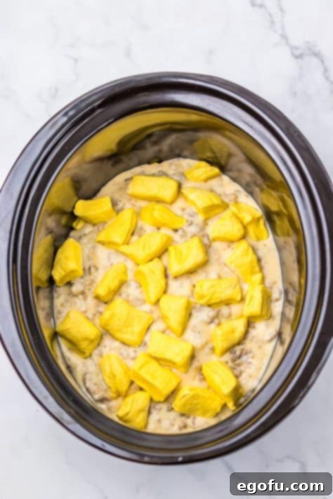 Biscuit dough, gravy and more biscuit dough pieces in a Slow Cooker.