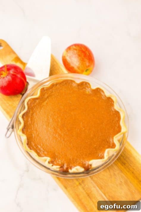 A beautifully baked Apple Butter Pie cooling on a wooden serving board, showcasing its golden crust and smooth, set filling.