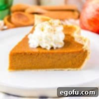 A small slice of Apple Butter Pie garnished with a swirl of whipped cream, resting on a stack of white plates.