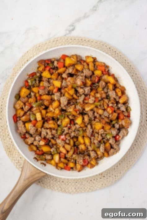 Sausage and veggies cooking in a skillet.