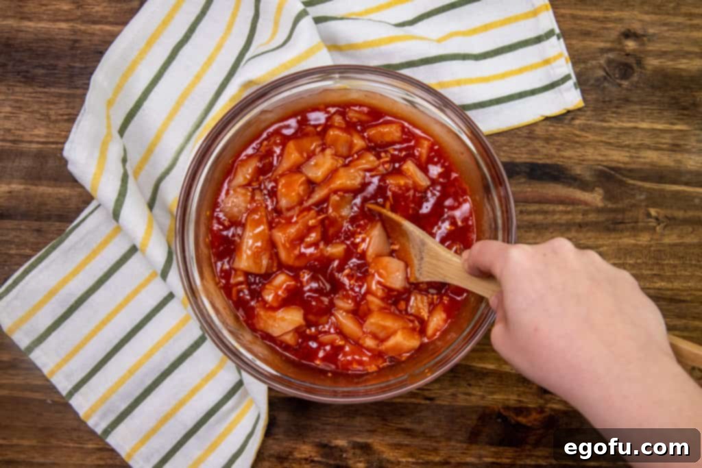 Sticky Sweet-Sour Chicken Bake 5 Chicken breasts added to a bowl containing a mixture of apricot preserves, Catalina dressing, and onion soup, ready to be stirred for the baked sweet and sour chicken recipe.