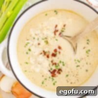 Looking down on a pot of Loaded Cauliflower Soup with a spoon.