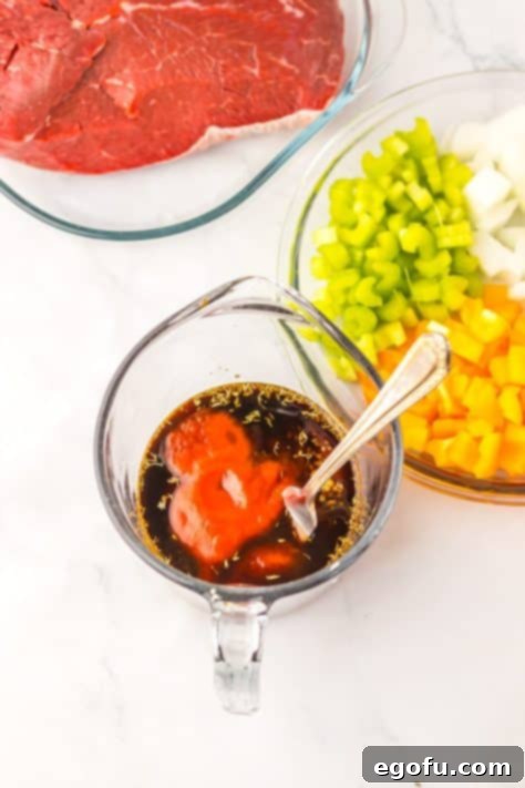 A mixing bowl with garlic, tomato sauce, bbq sauce, Worcestershire sauce, beef bouillon, thyme and water.