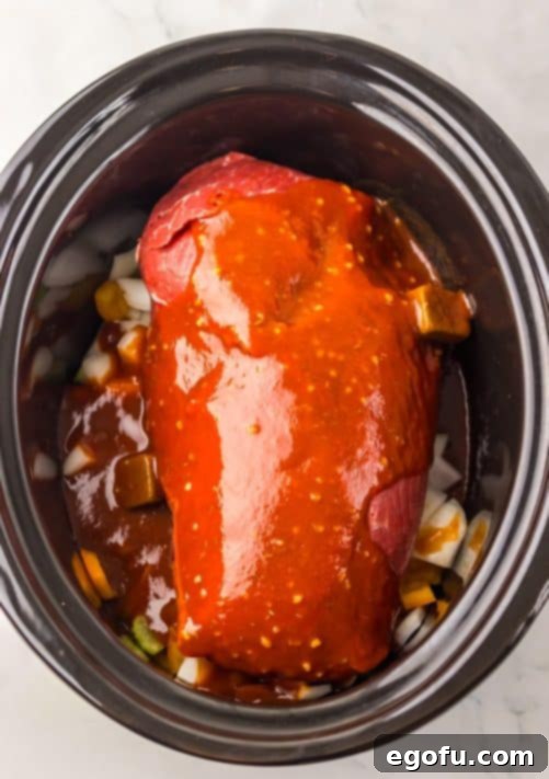 A pot roast covered in a sauce sitting in a Slow Cooker.