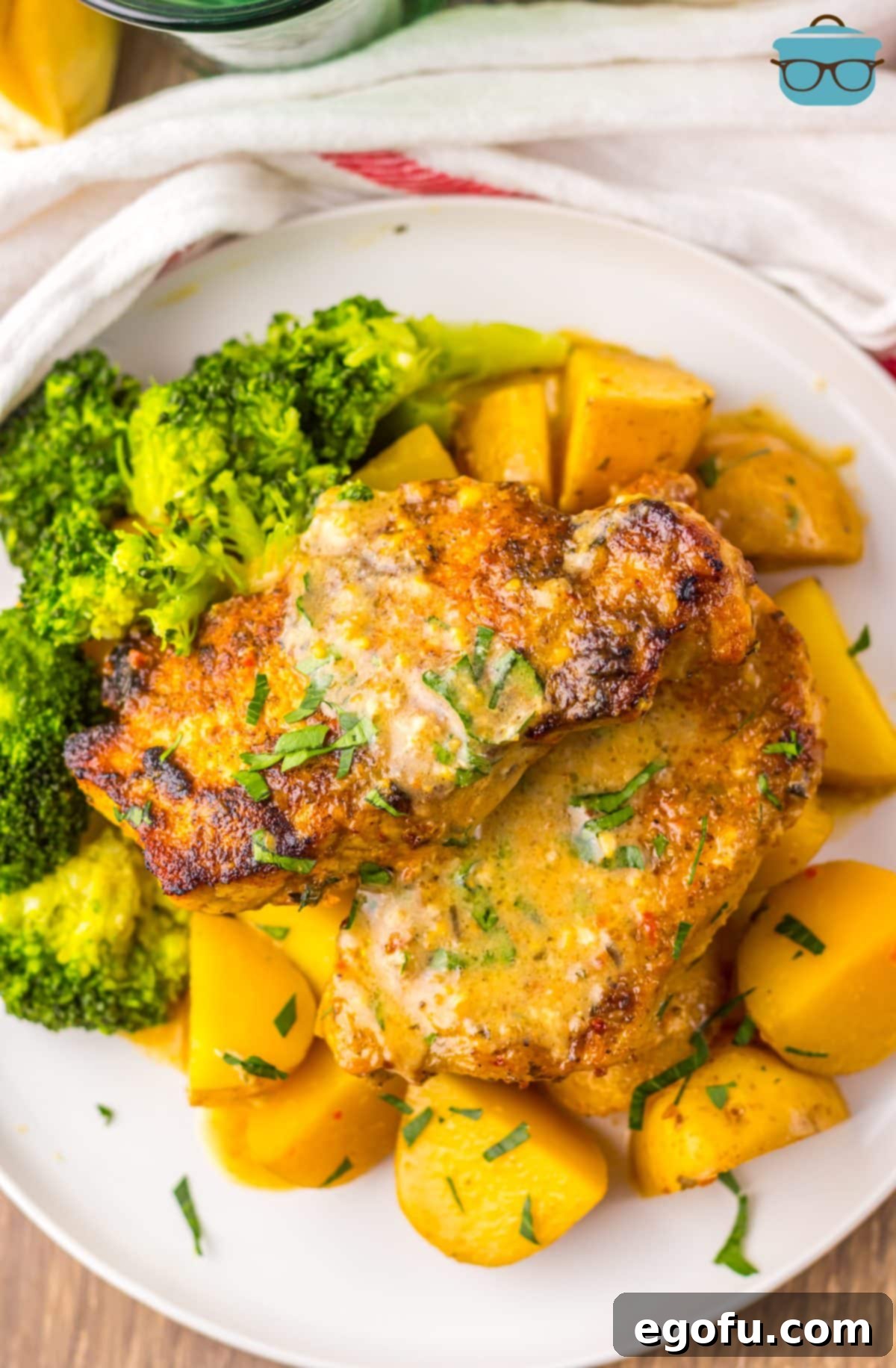A plate of Garlic Parmesan Pork Chops with potatoes and broccoli.