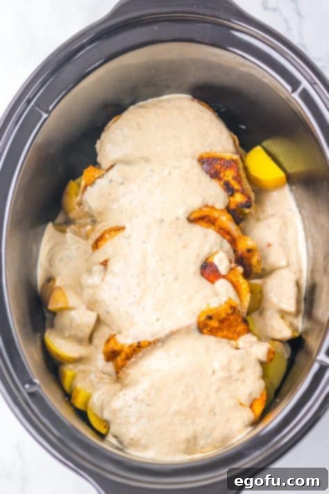 Sauce covering pork chops and potatoes in a Slow Cooker.