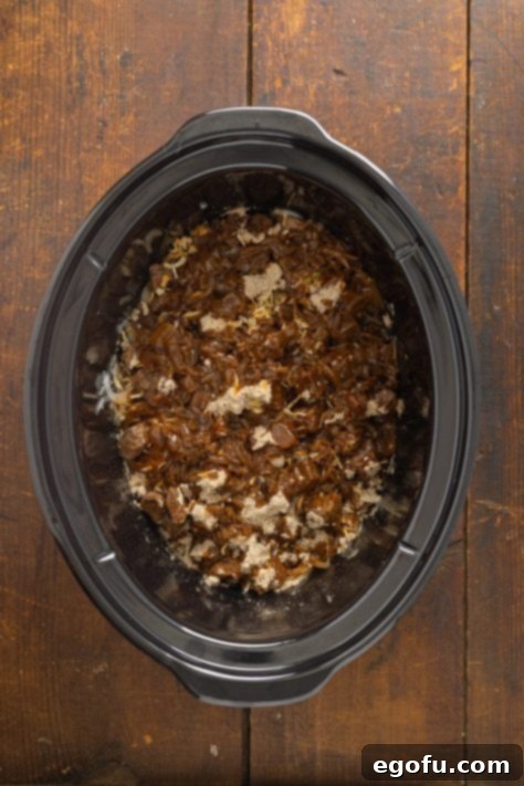 Crock Pot with onions, beef, and seasonings.