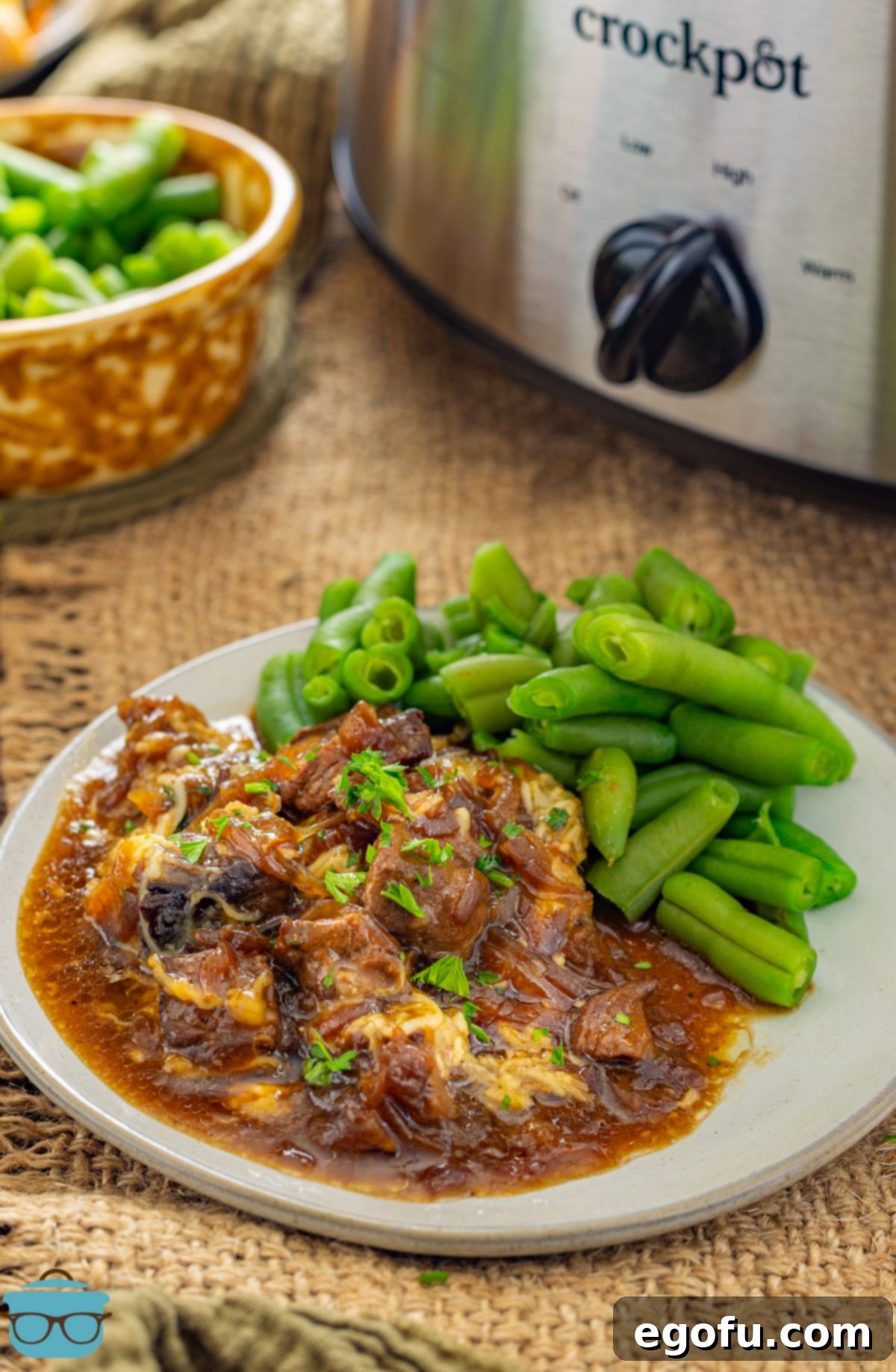 A plate of French Onion Beef Tips with gravy and green beans.