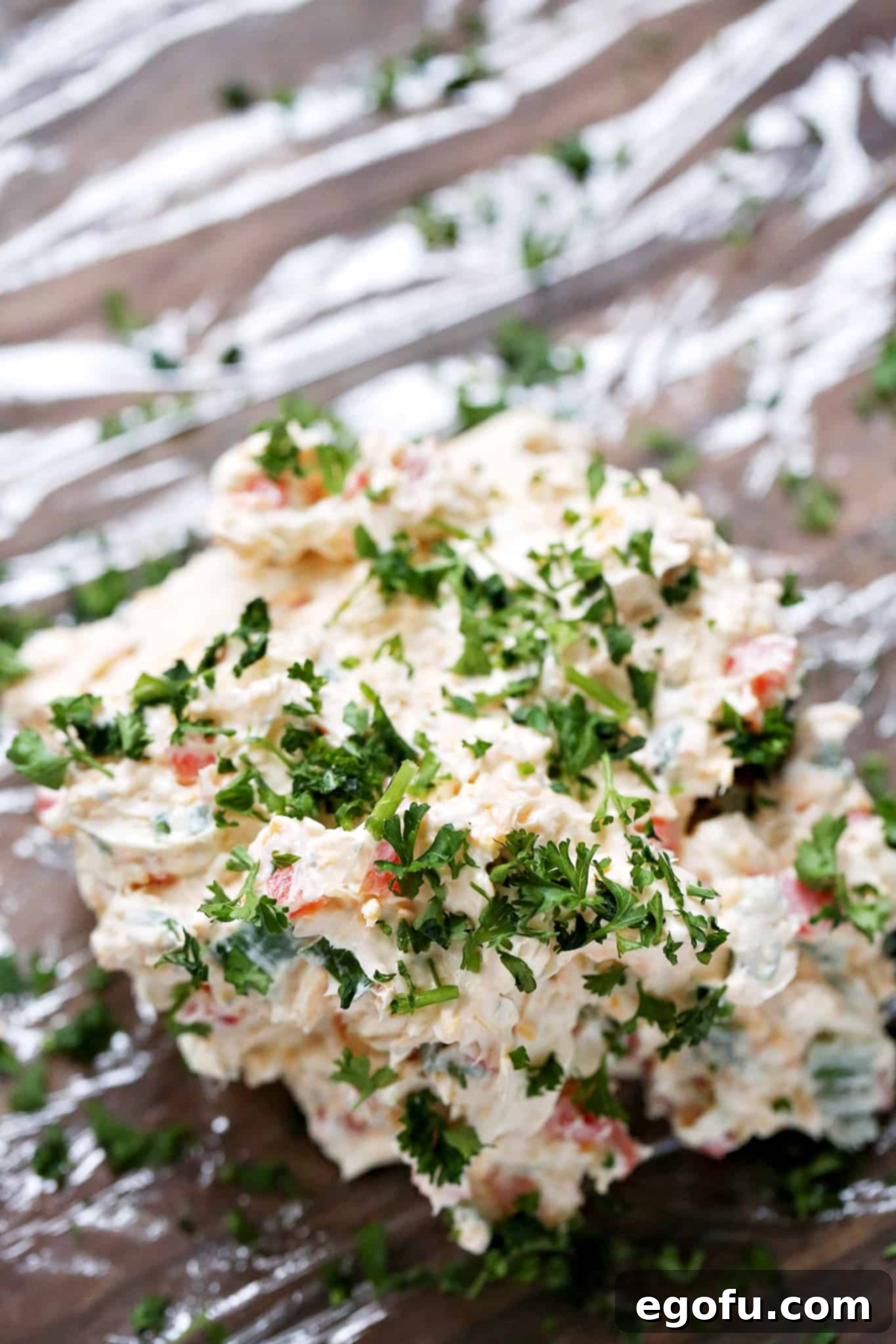 chopped parsley sprinkled on top of cream cheese mixture on plastic wrap.
