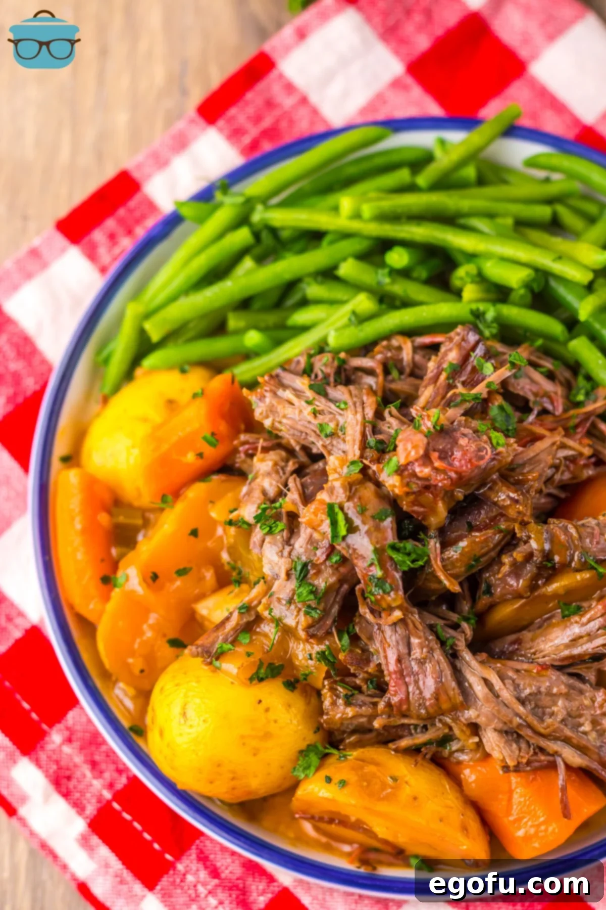 Close up looking down on a plate of veggies with Catalina Roast Beef and sauce. 
