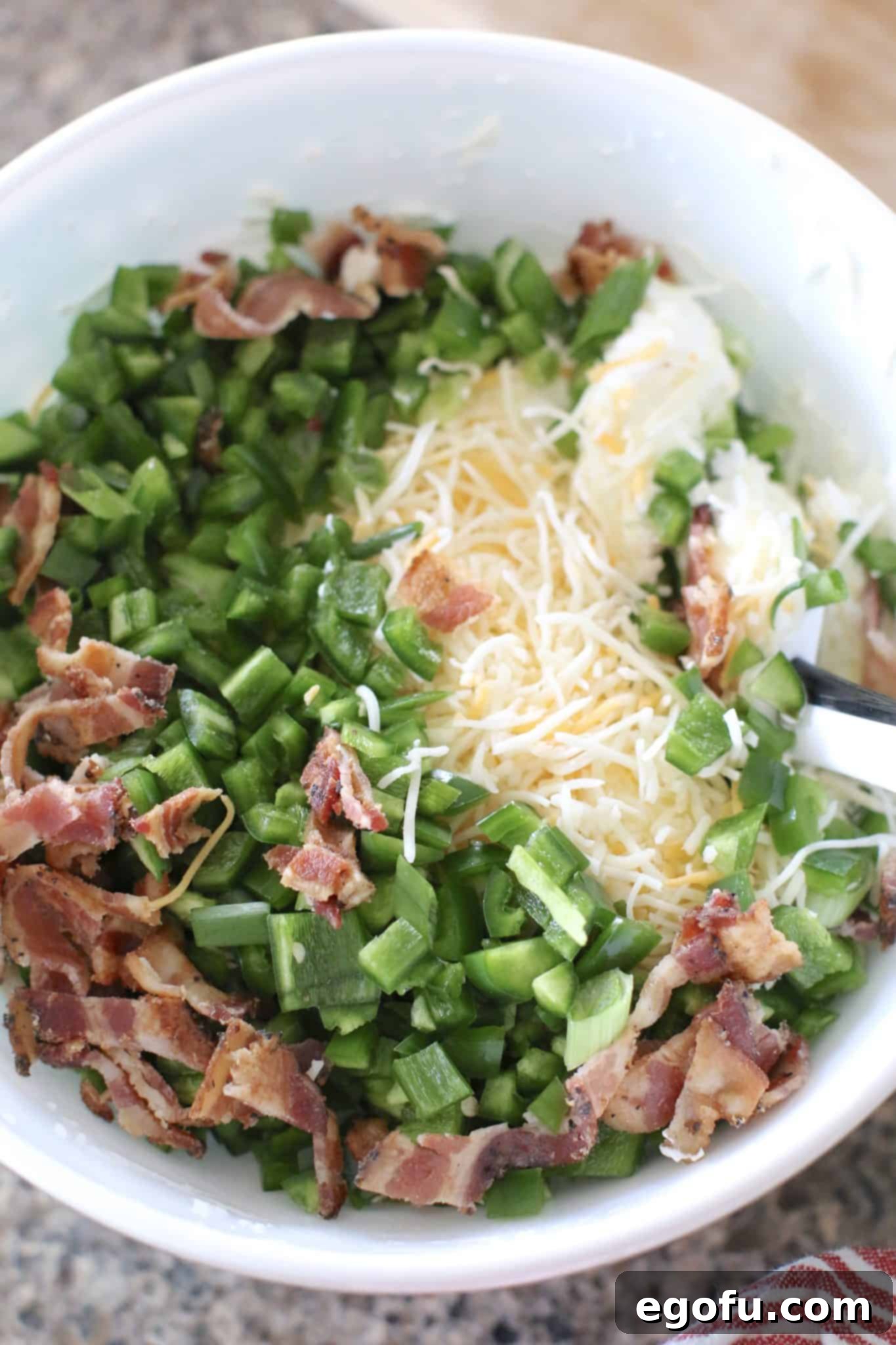 cream cheese, sour cream, bacon and shredded cheese in a bowl.