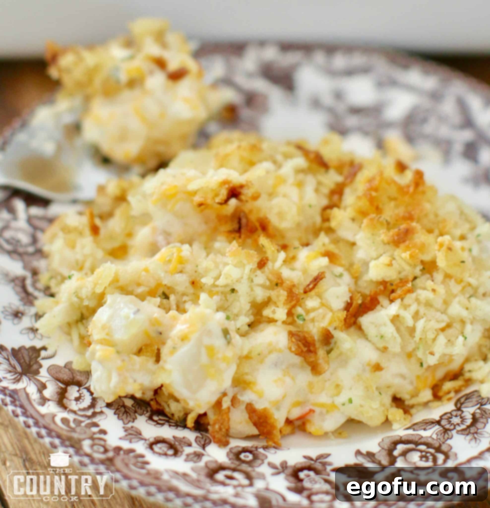 A single serving of Funeral Potatoes presented on a brown and white Spode plate, ready to be enjoyed.